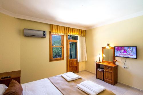a bedroom with a bed and a tv on the wall at Yeşilkaya Hotel in Kayakoy