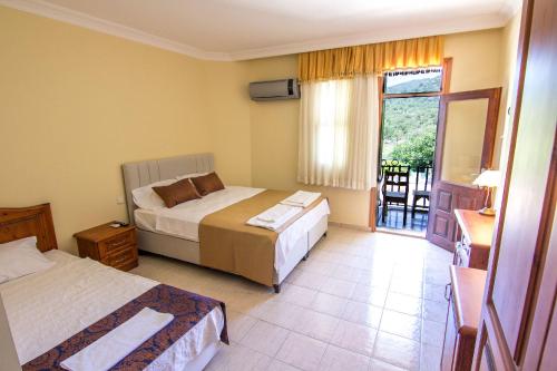een hotelkamer met 2 bedden en een balkon bij Yeşilkaya Hotel in Kayakoy