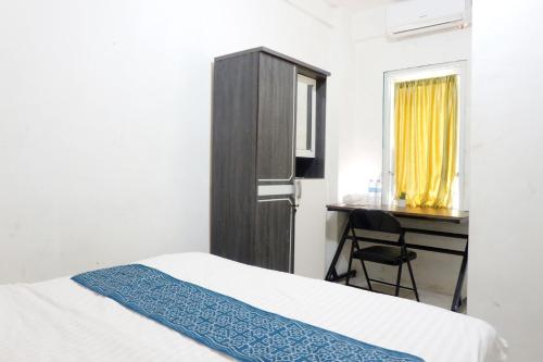 a bedroom with a bed and a desk and a chair at Kasmarani Homestay in Palembang