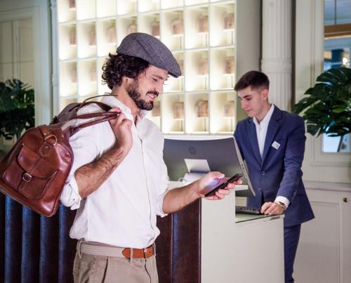 a man with a bag looking at a cell phone at Hotel Regina in Madrid