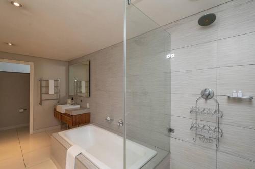 a bathroom with a tub and a glass shower at Canal-side Serenity in Cape Town