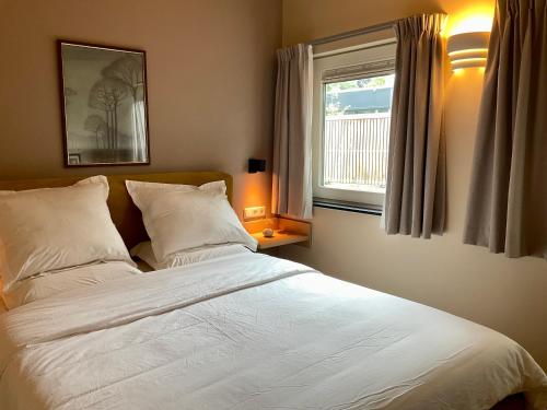 a bedroom with a white bed with a window at B&B Het Postkantoortje in Gorssel