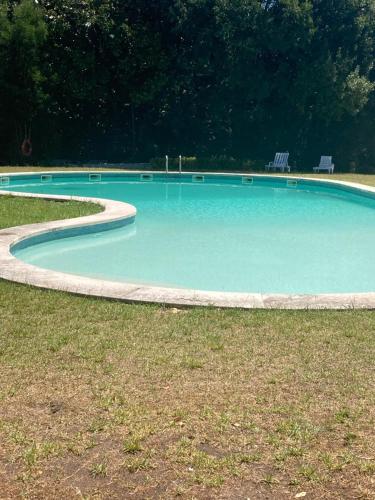 a large blue pool with two chairs in the grass at Palácio da Quinta da Portela II in Coimbra