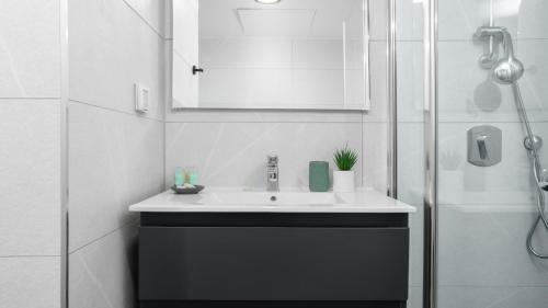 une salle de bain blanche avec un lavabo et une douche dans l'établissement סוויטה בסי סייד עם מרפסת - By Edomlux, à Eilat