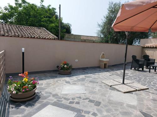 a patio with an umbrella and flowers in pots at Casa Sautu-fau in Santa Venerina