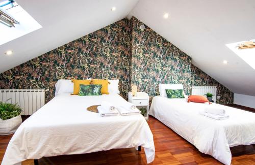 2 camas en un dormitorio del ático con papel pintado con motivos florales en CASA COMPLETA EN SANTIAGO, HASTA 9 HUÉSPEDES, en Santiago de Compostela