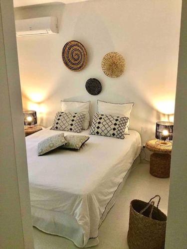 une chambre avec un lit avec des draps blancs et des oreillers dans l'établissement La Maison du Bonheur F5 jardin et piscine, à Narbonne