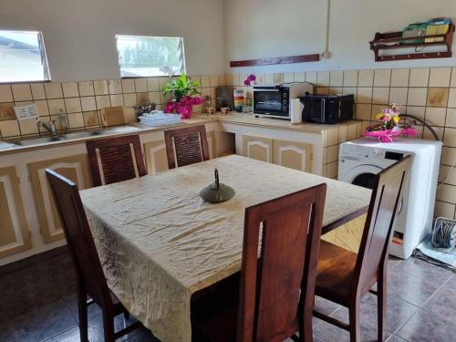 eine Küche mit einem Tisch und Stühlen sowie eine Küche mit einem Herd in der Unterkunft Ti kaz Vanille in Saint-Philippe