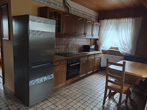 a kitchen with a stainless steel refrigerator and a table at Appartement am Waldesrand in Gifhorn