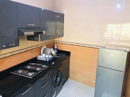 una piccola cucina con piano cottura e frigorifero di Charmant appartement ad Al-Ḥoseyma