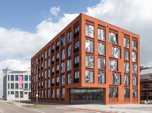 a large brick building with many windows on a street at Aparthotel Timmerfabriek Apartments I Kloeg Collection in Vlissingen