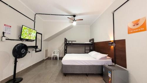 um quarto com uma cama e uma televisão de ecrã plano em Suíte n° 03 - Praia das Pitangueiras no Guarujá