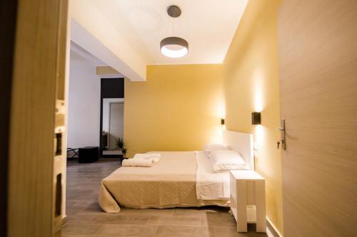 a bedroom with a bed and a yellow wall at Akheilos in Soverato Marina