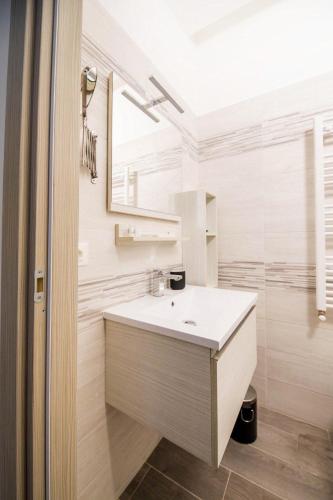 a white bathroom with a sink and a mirror at Akheilos in Soverato Marina