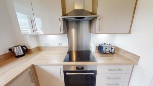 a kitchen with white cabinets and a stove top oven at 10 Bynack House in Aviemore