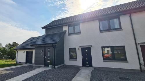 a white house with black doors and windows at 10 Bynack House in Aviemore