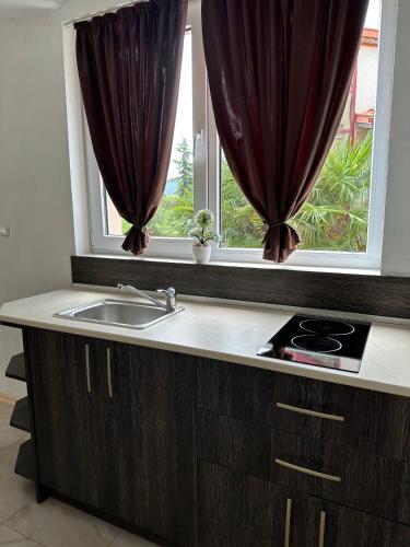 a kitchen with a sink and a window with curtains at Къща за гости Golden Reef in Tsarevo
