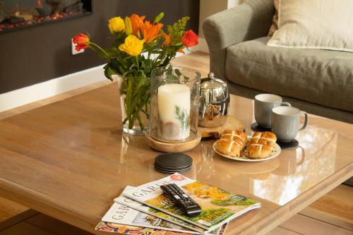 a coffee table with a vase of flowers and bread at Dalnaglar in Nethy Bridge