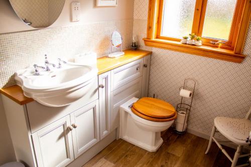 a bathroom with a sink and a toilet with a wooden seat at Longfield, Daviot in Inverness