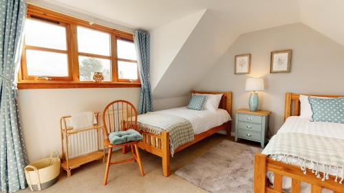 1 dormitorio con 2 camas individuales y ventana en Longfield, Daviot, en Inverness