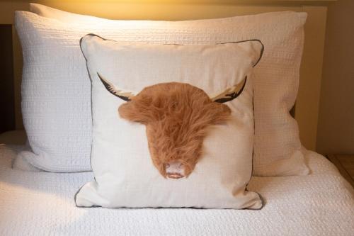 a cow head on a pillow on a bed at Dalnaglar in Nethy Bridge