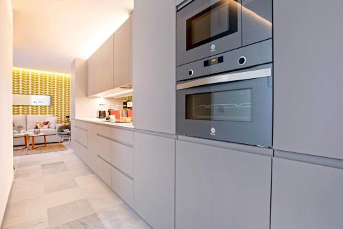 a kitchen with white cabinets and a microwave at Genteel Home Catedral in Cádiz