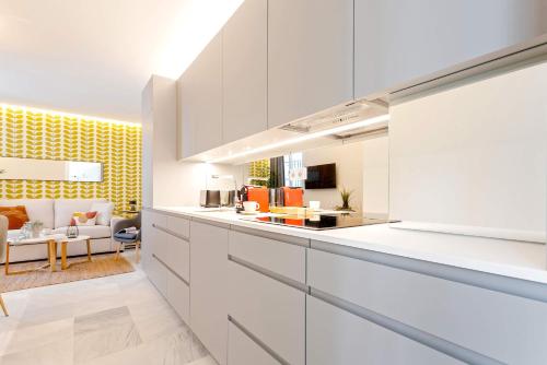 a kitchen with white cabinets and a living room at Genteel Home Catedral in Cádiz