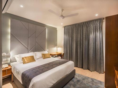 a hotel room with a large bed and a window at De Mandarin in Bengaluru