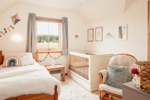 a childs bedroom with a crib and a chair at Balnagowan Cottage in Nethy Bridge