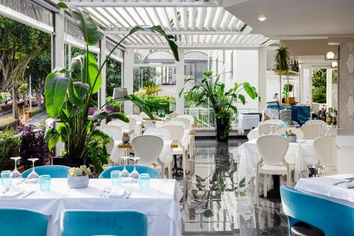 un ristorante con tavoli bianchi e sedie blu di Villa Zaccardi a Roma