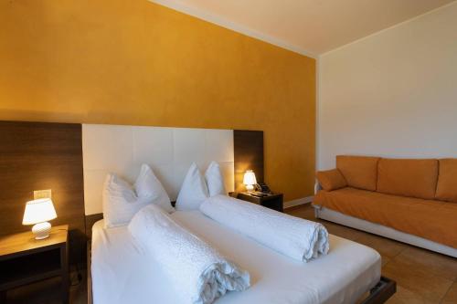 a bedroom with a white bed and a couch at Villa Ginevra Resort Agrituristico in Ficarra
