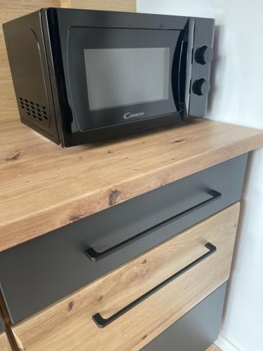 a microwave oven sitting on top of a wooden shelf at Apartament Centrum II in Lidzbark Warmiński
