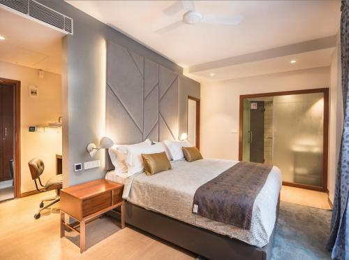a bedroom with a large bed and a desk at De Mandarin in Bangalore