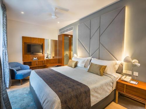 a hotel room with a large bed and a television at De Mandarin in Bengaluru