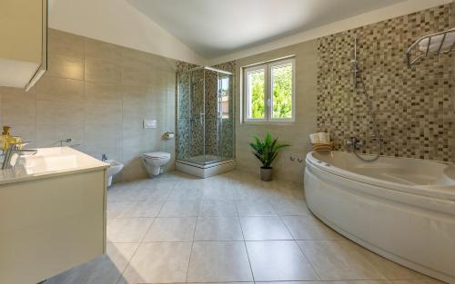 a bathroom with a tub and a sink and a toilet at Lotus Villas Resort in Pula