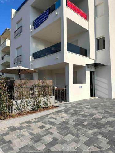 a large white building with an umbrella in front of it at Cosy new apartment near the sea in Grebaštica