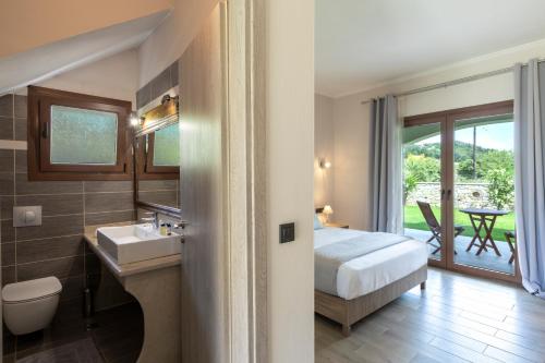 ein Schlafzimmer mit einem Bett und ein Badezimmer mit einem Waschbecken in der Unterkunft ERIKOUSA Palace by Corfuescapes in Ereikoússa