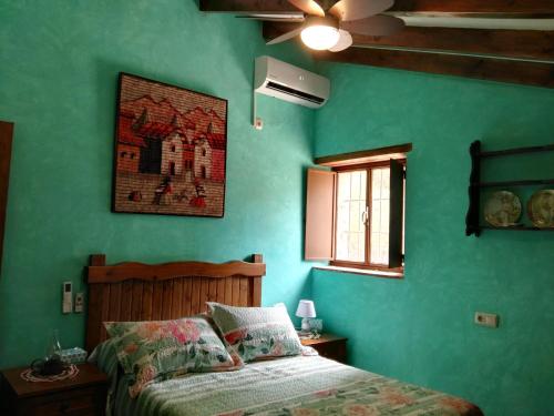 um quarto verde com uma cama e uma ventoinha de tecto em Pinar El Almendra em Málaga