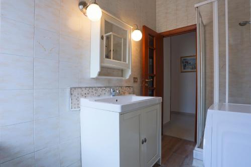 een badkamer met een witte wastafel en een spiegel bij Bright Apartment near the sea with parking in Salerno