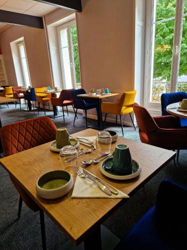una mesa con platos y utensilios en un restaurante en La Souveraine, en Contrexéville