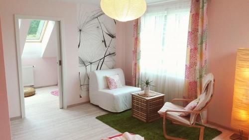 a living room with a white chair and a window at Vila Květ in Třeboň