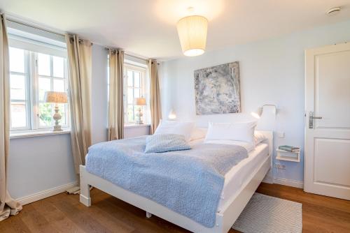 ein Schlafzimmer mit einem weißen Bett mit einer blauen Decke in der Unterkunft Gelys Huus in Midlum