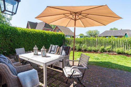 a table and chairs with an umbrella on a patio at Gelys Huus in Midlum