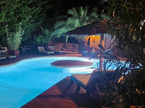 una piscina por la noche con mesa y sillas en Le Mas d'Olivier, en Le Plan-de-la-Tour