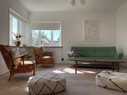 uma sala de estar com um sofá verde e cadeiras em Large house with sea view em Kivik