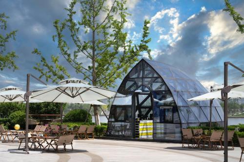 a glass building with tables and chairs and umbrellas at Le Meridien Xi'an Chanba in Xi'an
