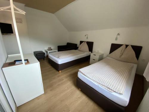 um pequeno quarto com 2 camas e uma cadeira em Pension Eder em Selzthal