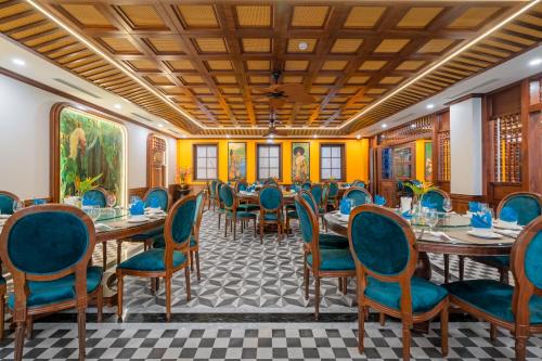 a dining room with tables and blue chairs at Grand Fleuve Boutique in Ha Long
