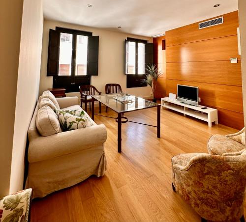 ein Wohnzimmer mit einem Sofa, einem Tisch und einem TV in der Unterkunft Penthouse near cathedral private rooftop Private Parking in Sevilla
