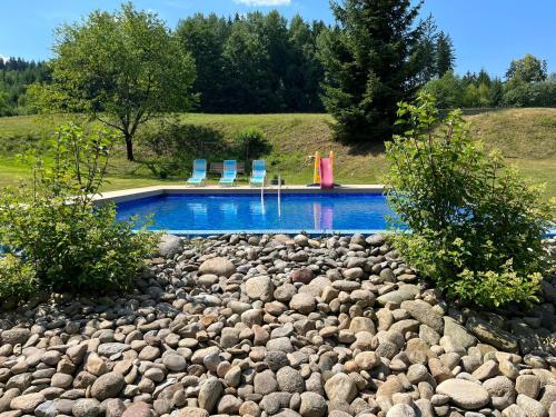 a rock pool with two chairs and a water slide at Ubytování Chotěvice in Hostinné